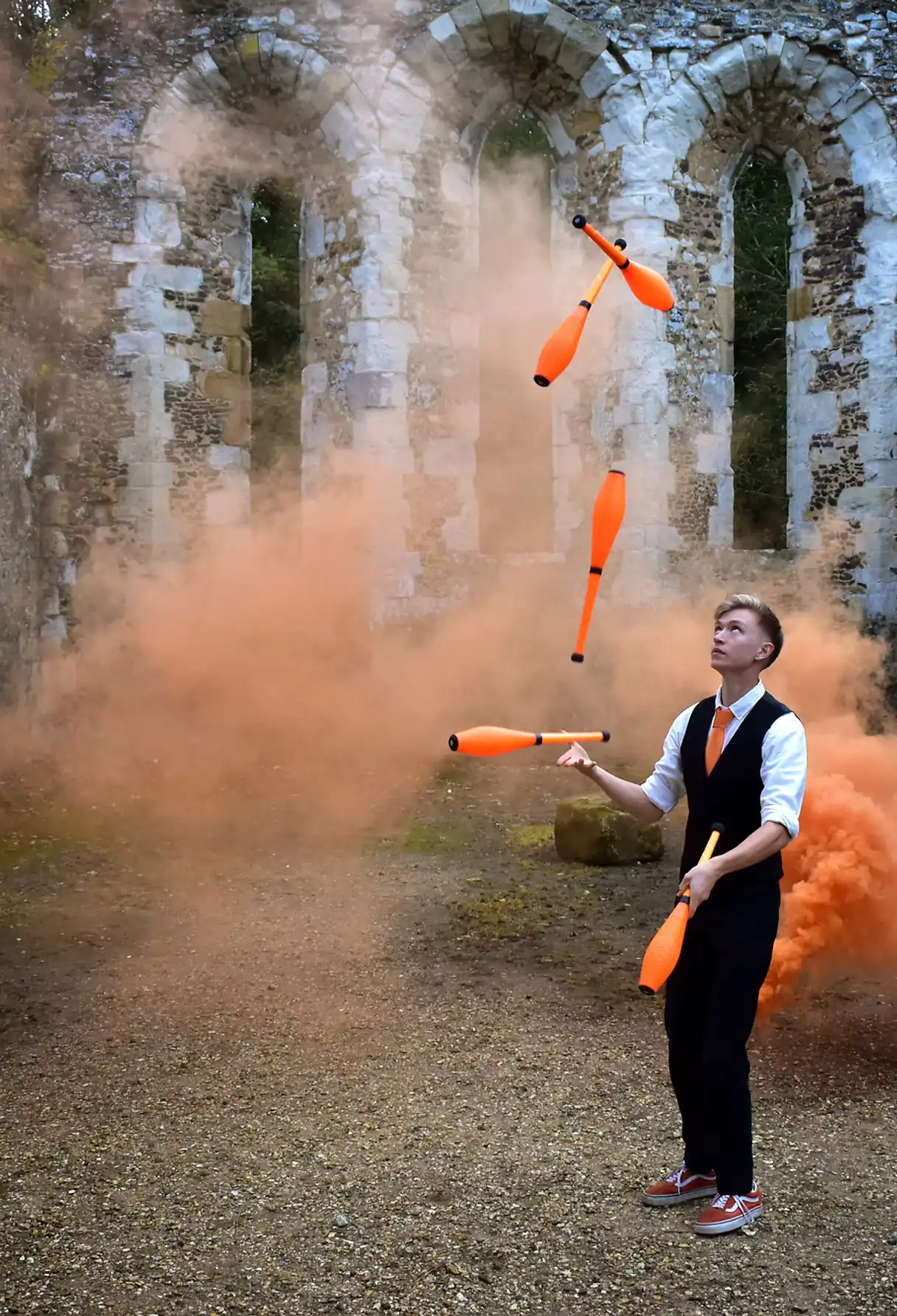Chris Welford juggles orange batons outside